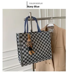 Detail of checkered canvas tote bag with a cute rabbit doll charm and navy blue straps