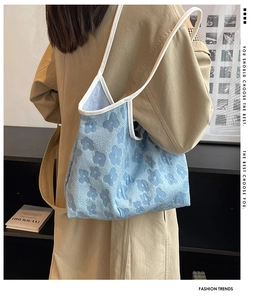 Detail of light blue floral knit tote bag showing relief texture and white handles