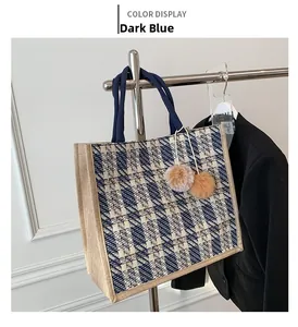 Detail of woven plaid tote bag with fuzzy pompom charms and dark blue rope handles