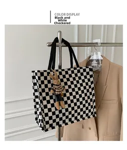 Detail of checkered canvas tote bag with a cute plush rabbit charm on a display stand