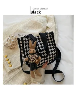 Detail of houndstooth tweed handbag featuring a cute rabbit charm and adjustable strap