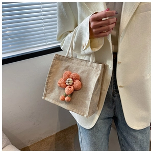 Detail showing the 3D orange floral decoration on the linen mini tote bag with rope handle