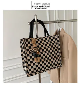 Detail of checkered canvas tote bag in black and khaki with a cute plush rabbit charm
