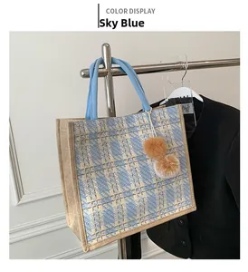 Detail of blue and beige tweed tote bag with plush ball charm on a metal hanger