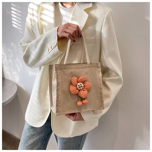 Close-up of linen lunch tote bag featuring a 3D orange plush flower decoration