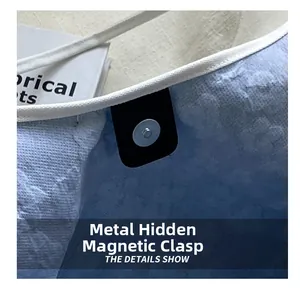 Detail showing the magnetic metal snap closure on a light blue canvas tote bag