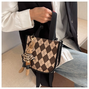 Details einer Vintage-Handtasche mit Rautenmuster, schwarzen Trägern und Hasenanhänger