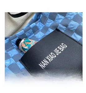 Detailed close-up of blue checkerboard tote bag featuring a black leather front pocket