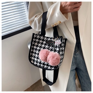 Détail du mini sac pied-de-poule avec breloques cerises en fausse fourrure rose sur bandoulière