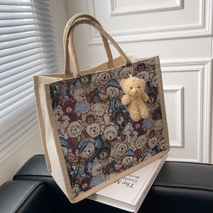 Beige linen tote bag featuring vintage bear patterns and a plush teddy charm accessory