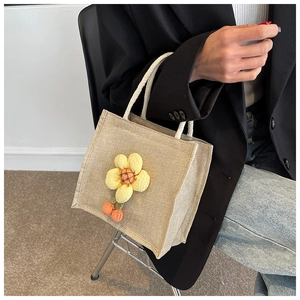 Detail of linen lunch bag with 3D yellow flower, orange pompoms and white woven handles