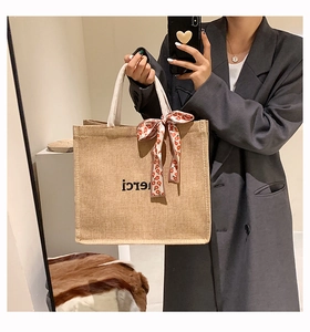 Détail du sac cabas en lin avec texte merci, poignée en corde et foulard à fleurs noué
