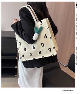 Detail of canvas tote bag with numeric print and green plush onion keychain charm