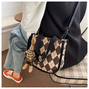 Detailansicht einer Vintage-Stepp-Tasche mit dekorativem Hasenanhänger und Schultergurt