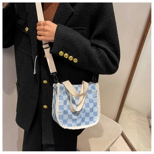 Sac seau en toile à damier bleu et blanc porté avec une veste noire chic