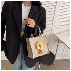 Close-up of linen tote bag featuring a 3D yellow flower and white woven handles
