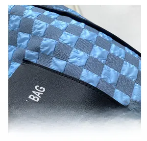 Close-up of blue checkerboard bubble fabric and leather base with brand logo details