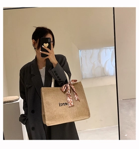 Détail d'un sac en lin avec imprimé merci et un ruban floral noué sur la poignée