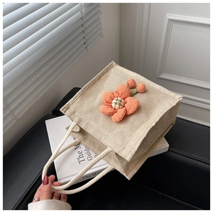 Detail of linen lunch bag featuring an orange plush flower and braided rope handles