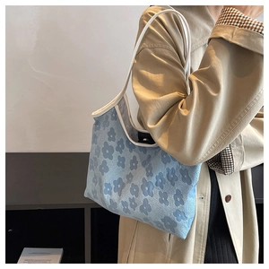 Detail view of light blue jacquard tote bag with dark blue floral patterns and white trim