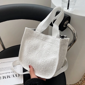 White canvas floral tote bag with textured relief pattern and wide shoulder strap