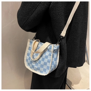Détail du mini sac cabas en toile à damier bleu porté en bandoulière par un mannequin