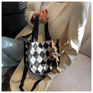 Detail der schwarz-weißen Argyle-Segeltuchhandtasche mit Strickhasen-Anhänger am Model