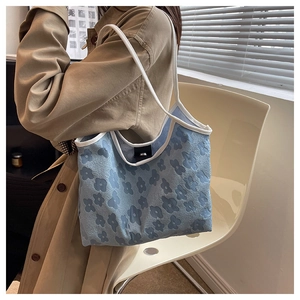Detail showing blue canvas tote bag with floral embossing and white leather strap