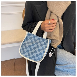 Détail du sac seau en toile à carreaux bleus avec bandoulière blanche et poignée élégante