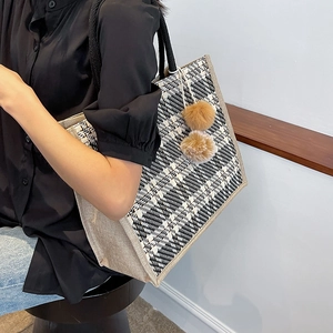 Large black and white checkered woven tote bag with rope handles and plush ball charms