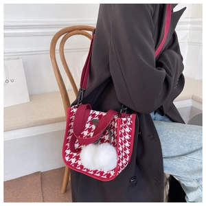 Détail du sac cabas en toile à motif pied-de-poule rouge avec pompon blanc et bandoulière
