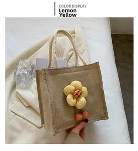 Detail of jute lunch bag featuring a yellow fabric flower and white cotton rope handle