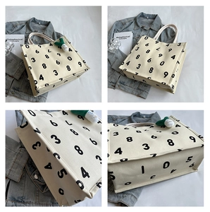 Detail of canvas tote bag featuring numeric print, rope handles, and plush onion charm