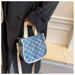 Détail du sac seau en toile à damier bleu avec des poignées tissées crème