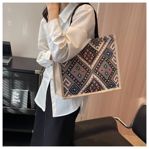 Detailed knit pattern on ethnic style tote bag worn by a model in office setting