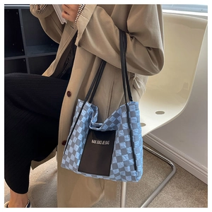 Close-up of quilted checkerboard tote bag in light blue and grey with black leather straps