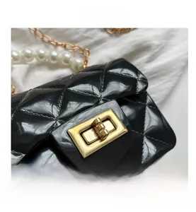Detail of black quilted jelly bag featuring gold clasp and pearl metal chain strap