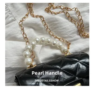 Close-up of black quilted patent leather bag with white pearl handle and gold chain strap