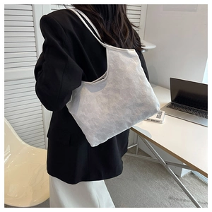 Detailed texture of white tote bag with embossed floral pattern and thin shoulder strap