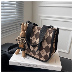 Detail der braunen Argyle-Stofftasche mit schwarzem Tragegurt und Hasenanhänger