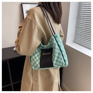 Detailed side view of checkerboard tote bag in mint green and grey with black straps