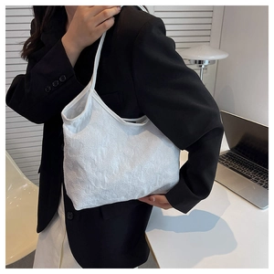 Detail of white canvas tote bag featuring 3D embossed floral texture on shoulder strap