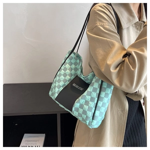 Detailed view of mint green quilted checkerboard tote bag worn with a beige trench coat