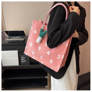 Detailed view of pink canvas tote bag with numeric print and cute plush pendant