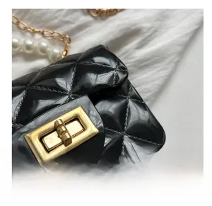 Close-up of black quilted jelly bag with gold swivel lock and pearl metal chain strap