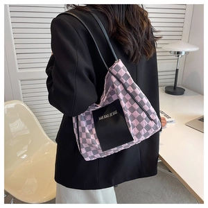 Detail view of pink and grey checkerboard tote bag worn with a black office blazer