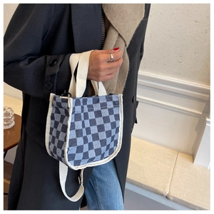 Détail du sac seau en toile damier bleu avec bandoulière ajustable sur un mannequin