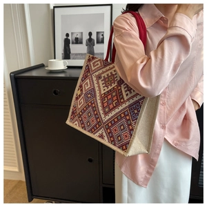 Detailed view of the woven geometric jacquard texture and red braided strap on the tote bag