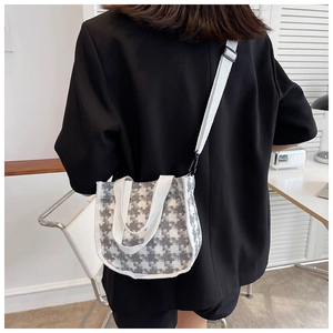 Détail d'un sac à motif pied-de-poule avec bandoulière réglable porté par un mannequin