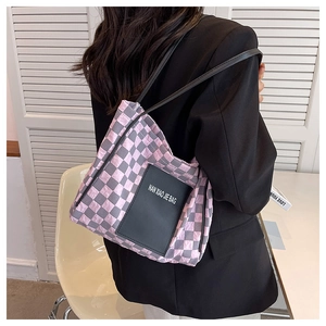 Checkerboard pattern tote bag with leather straps worn over a black blazer